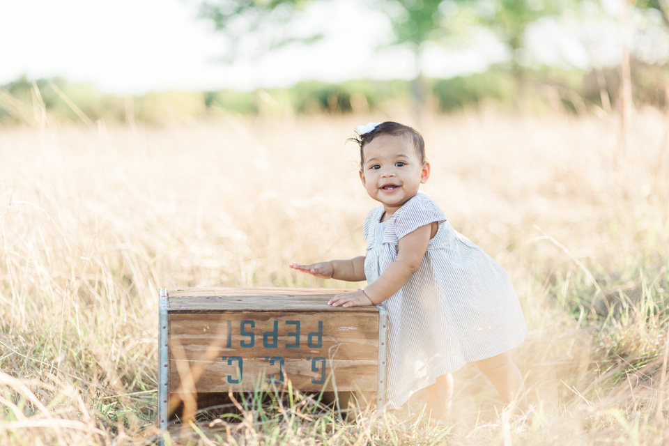 adorable little girl next to crate in field