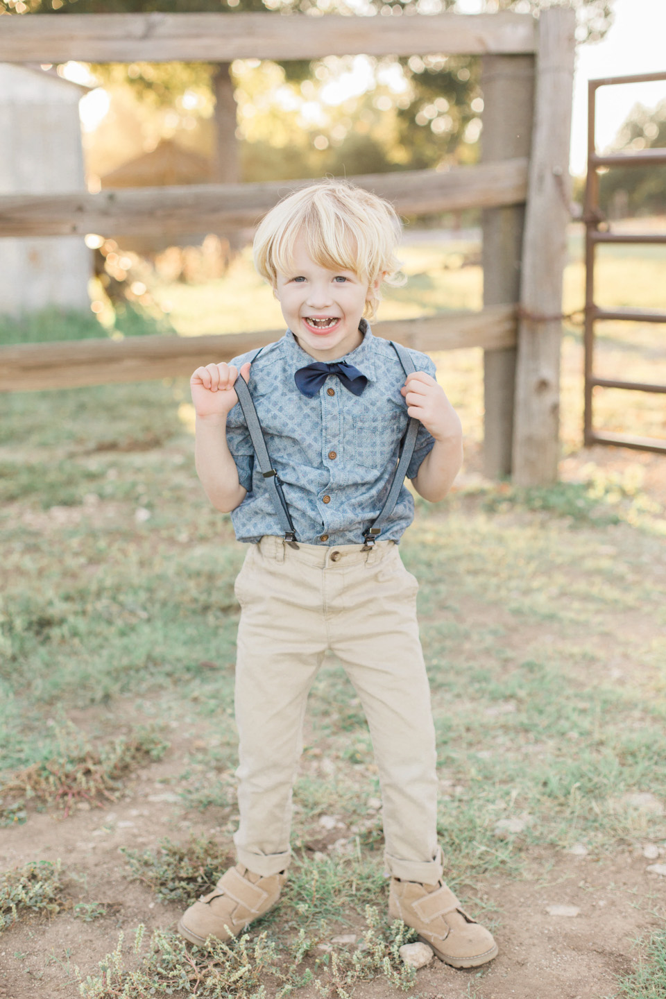 little boy in suspenders in grassy field by austin texas photographer 